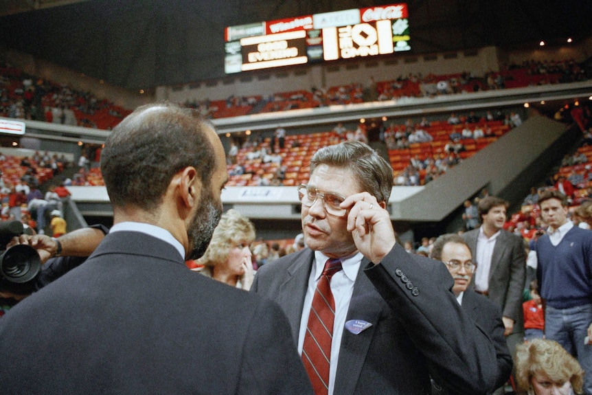 Ben Jones wearing a suit in a sporting stadium.